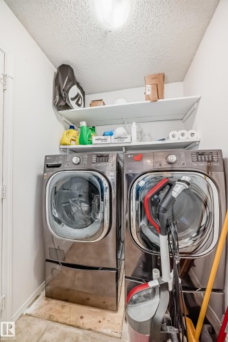 Laundry room with a textured ceiling, washing machine and dryer, and tile patterned flooring - #48 - 2503 24 Street Nw, Edmonton, AB - Indoor Photo Showing Laundry Room