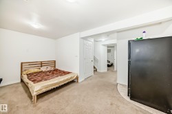Bedroom featuring freestanding refrigerator and light carpet - 
