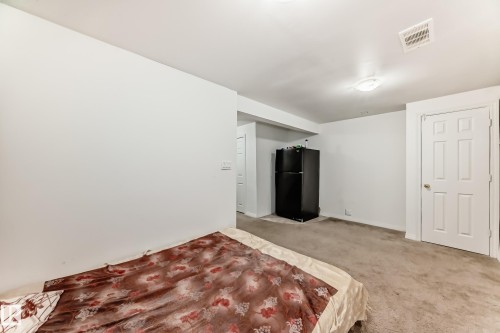 Unfurnished bedroom with freestanding refrigerator and carpet flooring - #48 - 2503 24 Street Nw, Edmonton, AB - Indoor