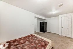 Unfurnished bedroom with freestanding refrigerator and carpet flooring - 
