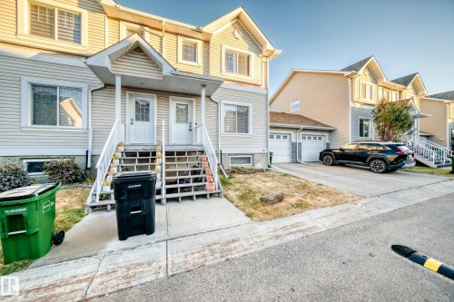 Traditional-style house featuring driveway, a garage, a residential view, and covered porch - #48 - 2503 24 Street Nw, Edmonton, AB - Outdoor With Facade