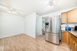 Kitchen featuring stainless steel fridge, a textured ceiling, light wood finished floors, light stone counters, and ceiling fan - 