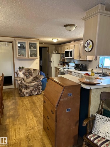 Kitchen with light wood-type flooring, a peninsula, white appliances, a textured ceiling, and light countertops - 37 43 Avenue, Millet, AB - Indoor Photo Showing Kitchen