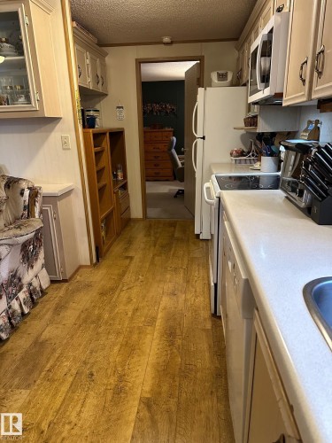 Kitchen featuring light countertops, light wood finished floors, white appliances, a textured ceiling, and light brown cabinets - 37 43 Avenue, Millet, AB - Indoor Photo Showing Kitchen