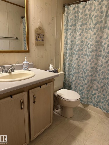 Full bath with vanity, curtained shower, wallpapered walls, and light tile patterned floors - 37 43 Avenue, Millet, AB - Indoor Photo Showing Bathroom