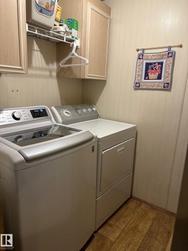 Laundry area featuring cabinet space, wood finished floors, and washer and dryer - 37 43 Avenue, Millet, AB - Indoor Photo Showing Laundry Room