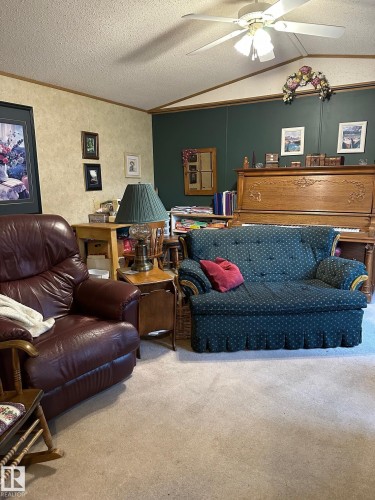 Carpeted living room with a textured ceiling, ornamental molding, ceiling fan, and vaulted ceiling - 37 43 Avenue, Millet, AB - Indoor Photo Showing Living Room