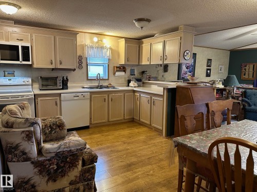 Kitchen with a textured ceiling, open floor plan, light wood-style floors, light countertops, and white appliances - 37 43 Avenue, Millet, AB - Indoor Photo Showing Kitchen With Double Sink