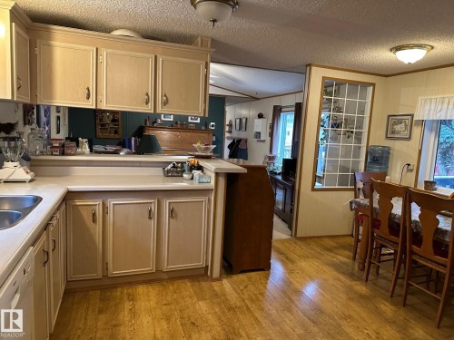 Kitchen featuring light brown cabinetry, light countertops, light wood-style flooring, ornamental molding, and dishwasher - 37 43 Avenue, Millet, AB - Indoor Photo Showing Kitchen With Double Sink