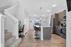 Kitchen featuring a breakfast bar area, gray cabinets, a center island with sink, decorative backsplash, and pendant lighting - 