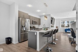 Kitchen featuring appliances with stainless steel finishes, gray cabinetry, light wood-type flooring, tasteful backsplash, and pendant lighting - 