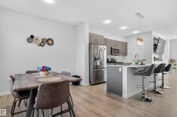 Kitchen featuring gray cabinets, a kitchen bar, appliances with stainless steel finishes, backsplash, and pendant lighting - 