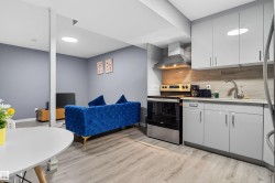 Kitchen with stainless steel appliances, light countertops, wall chimney range hood, and light wood-style flooring - 