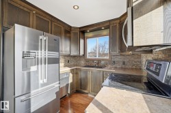 Kitchen featuring stainless steel appliances, light countertops, decorative backsplash, dark wood finished floors, and dark brown cabinets - 