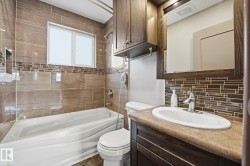 Bathroom featuring vanity, washtub / shower combination, and tasteful backsplash - 
