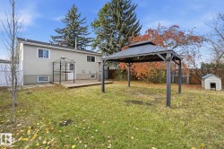 Back of property with a gazebo, a fenced backyard, a storage unit, and stucco siding - 