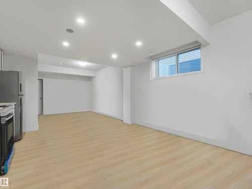 Basement featuring light wood finished floors, recessed lighting, and freestanding refrigerator - 2412 14 Avenue, Edmonton, AB - Indoor Photo Showing Basement