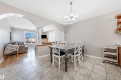 Dining space featuring arched walkways, decorative columns, a chandelier, and light tile patterned flooring - 