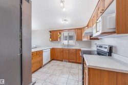 Kitchen featuring white appliances, light countertops, brown cabinetry, and a textured ceiling - 