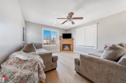 Living area with a textured ceiling, light wood-style floors, attic access, a glass covered fireplace, and ceiling fan - 