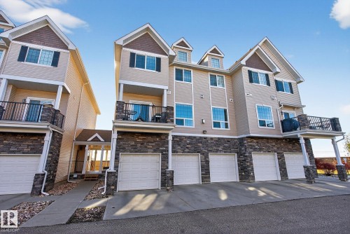 Back of property with a balcony, a garage, stone siding, and driveway - 117 7293 South Terwillegar Drive, Edmonton, AB - Outdoor With Balcony With Facade