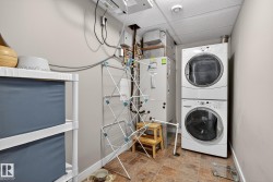 Laundry area featuring a paneled ceiling, stacked washer and clothes dryer, heating unit, and stone finish floors - 