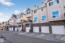 View of building exterior featuring a residential view, an attached garage, and driveway - 