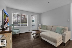 Sitting room with a textured ceiling, dark wood-style floors, and a baseboard heating unit - 
