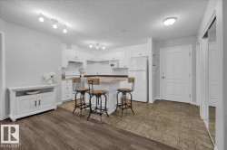 Kitchen featuring white cabinets, white appliances, decorative backsplash, a textured ceiling, and a breakfast bar area - 