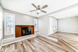 Unfurnished living room with light wood finished floors, a glass covered fireplace, and a ceiling fan - 