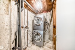 Washroom featuring unfinished concrete floors and stacked washer / drying machine - 