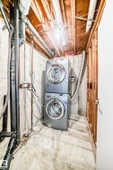 Unfinished basement featuring stacked washer and clothes dryer - 