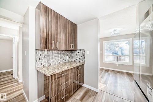Bar with freestanding refrigerator, light stone countertops, light wood finished floors, decorative backsplash, and modern cabinets - 44 4403 Riverbend Road, Edmonton, AB - Indoor Photo Showing Other Room