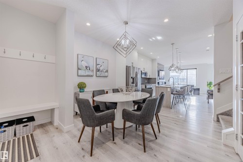 Dining area featuring stairway, light wood finished floors, a chandelier, recessed lighting, and a textured ceiling - 8086 Kiriak Link, Edmonton, AB - Indoor Photo Showing Dining Room