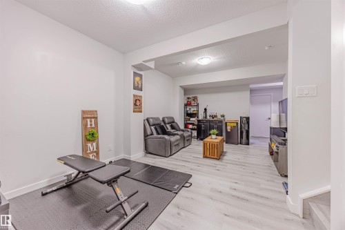 Workout room featuring a textured ceiling, a bar, and light wood-type flooring - 8086 Kiriak Link, Edmonton, AB - Indoor