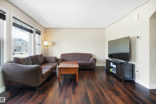 Living area featuring dark wood-type flooring and a textured ceiling - 1442 33A Street Nw, Edmonton, AB - Indoor Photo Showing Living Room