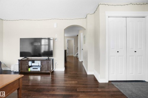 Hallway featuring arched walkways, a textured ceiling, and dark wood finished floors - 1442 33A Street Nw, Edmonton, AB - Indoor Photo Showing Other Room