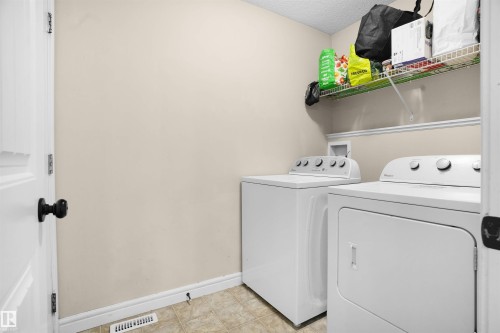 Laundry area featuring a textured ceiling, separate washer and dryer, and light tile patterned floors - 1442 33A Street Nw, Edmonton, AB - Indoor Photo Showing Laundry Room