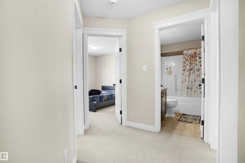 Hallway with light colored carpet and a textured ceiling - 1442 33A Street Nw, Edmonton, AB - Indoor