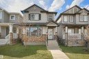 View of front of house featuring stone siding, covered porch, and a front lawn - 1442 33A Street Nw, Edmonton, AB  - Outdoor With Deck Patio Veranda With Facade 