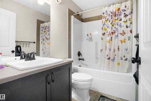 Full bath featuring vanity, shower / tub combo with curtain, and light tile patterned flooring - 1442 33A Street Nw, Edmonton, AB - Indoor Photo Showing Bathroom