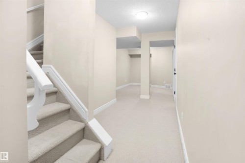 Staircase with a textured ceiling and carpet floors - 1442 33A Street Nw, Edmonton, AB - Indoor Photo Showing Other Room