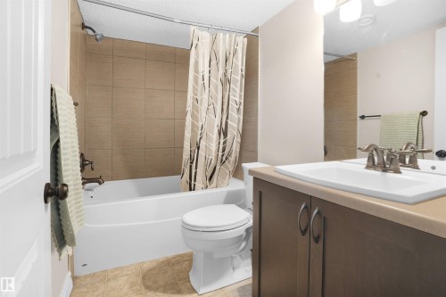 Full bathroom with vanity, shower / tub combo with curtain, light tile patterned floors, and a textured ceiling - 1442 33A Street Nw, Edmonton, AB - Indoor Photo Showing Bathroom