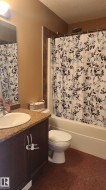 Full bathroom with a textured ceiling, vanity, and shower / tub combo with curtain - 