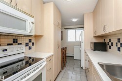 Kitchen featuring tasteful backsplash, white appliances, light brown cabinetry, light countertops, and a textured ceiling - 