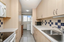 Kitchen with tasteful backsplash, light brown cabinets, white appliances, light countertops, and a textured ceiling - 