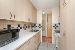 Kitchen with light brown cabinetry, white appliances, light tile patterned floors, tasteful backsplash, and a textured ceiling - 