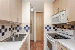 Kitchen featuring white appliances, light brown cabinets, light countertops, light wood-style flooring, and a textured ceiling - 
