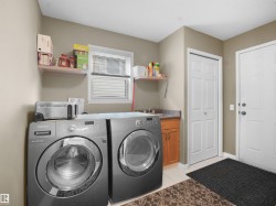 Laundry area with light tile patterned floors, washer and dryer, and cabinet space - 
