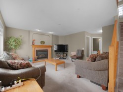 Carpeted living area featuring a glass covered fireplace and stairway - 
